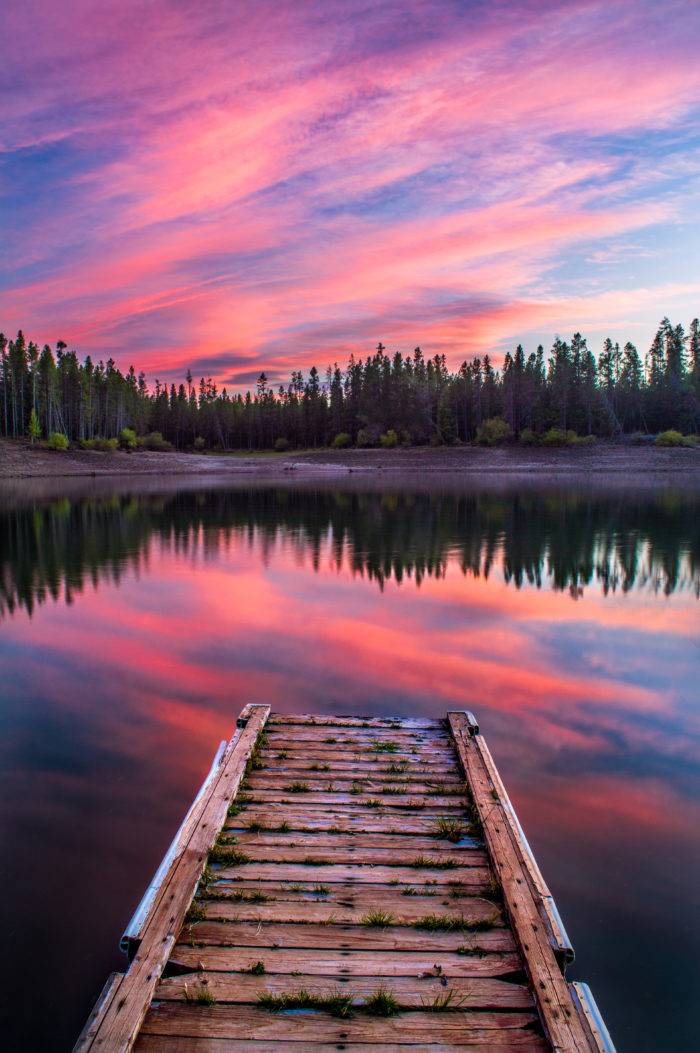 sunset over a dock floating in the water.