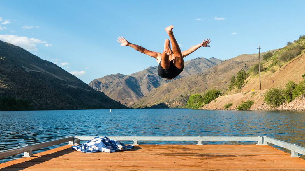 man jumping off dock into the water