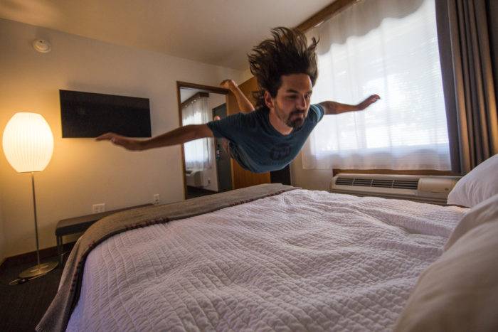 man jumping on bed