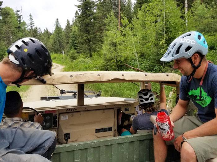 Two cyclists on an old military vehicle.