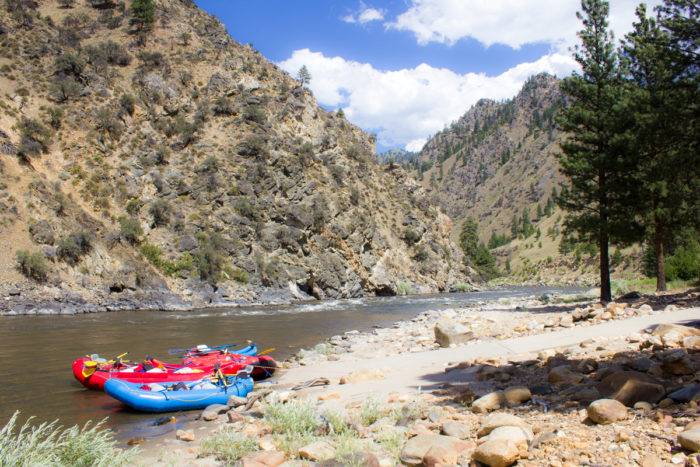 rafts sitting in the Salmon River with mountains in background