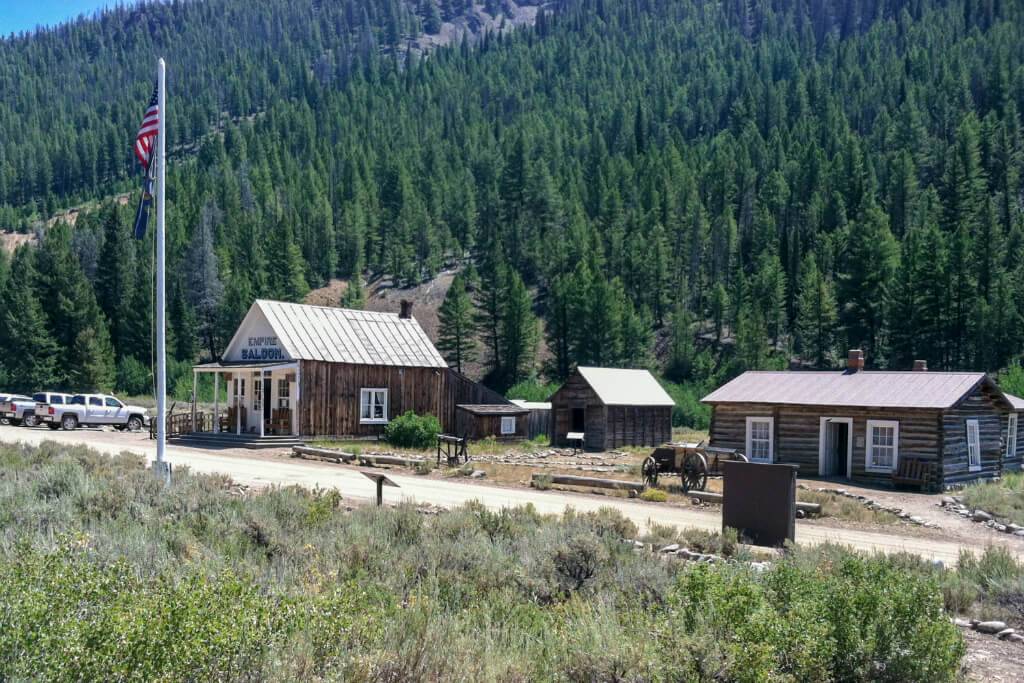 Various historic buildings at the base of a tree-covered mountain at Custer Ghost Town.