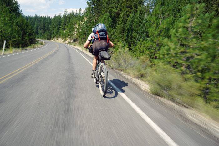 cyclist riding along a paved road in the mountains