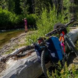 woman fishing on mountain river with mountain bike in foreground