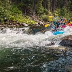 A group of rafters laugh as they adventure across whitewater Middle Fork rapids splashing on the Salmon River.