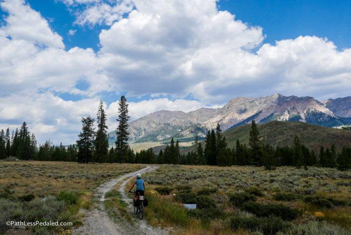 cyclist riding a trail with mountains in the background