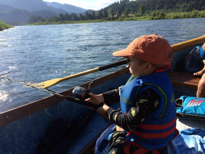 little boy fishing from a drift boat