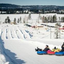 people snow tubing down hill with designated lanes at the McCall Activity Barn.