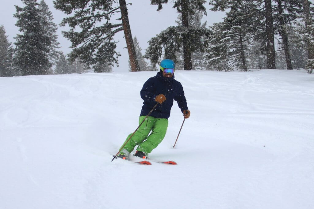 A man wearing green pants skis down a slope at Snowhaven Ski and Tubing Area.