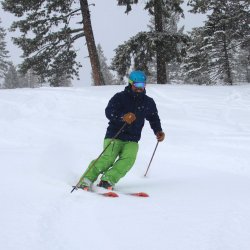 A man wearing green pants skis down a slope at Snowhaven Ski and Tubing Area.