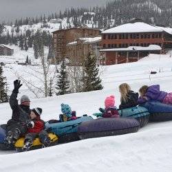 Family tubing down a hill in winter