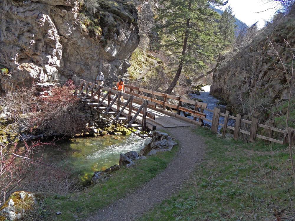 two people walking across a mountain bridge