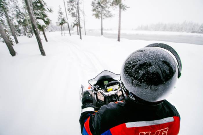 A snowmobiler heading through trees at Island Park, Idaho.