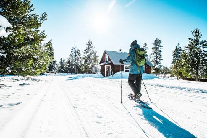 A person in a blue jacket snowshoes at Harriman State Park.