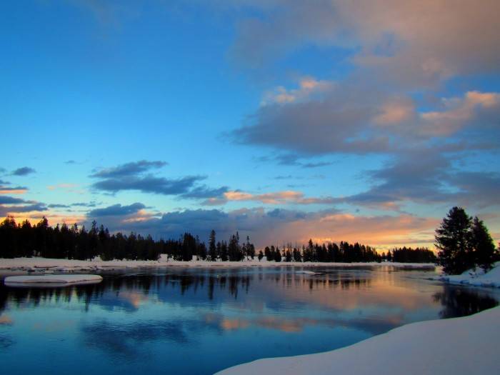 Snow-covered banks surround the calm waters reflecting evening clouds.