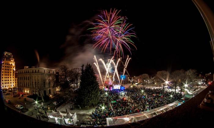 Fireworks exploding while the giant idaho potato is lowered in front of the capital at night. 