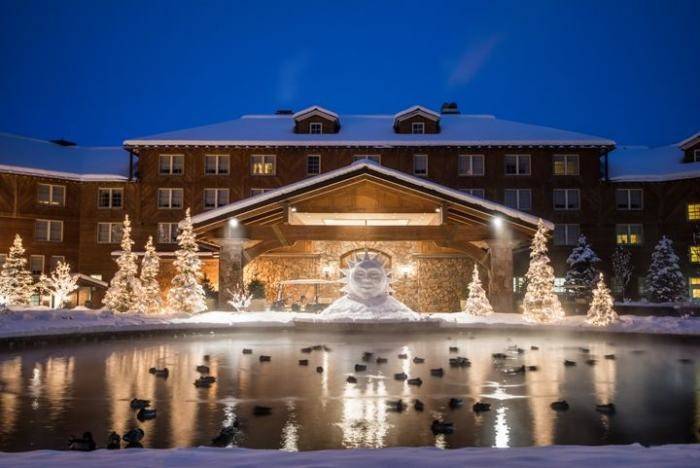 Picture of the Sun Valley Lodge at night with lighted Christmas trees in front. 