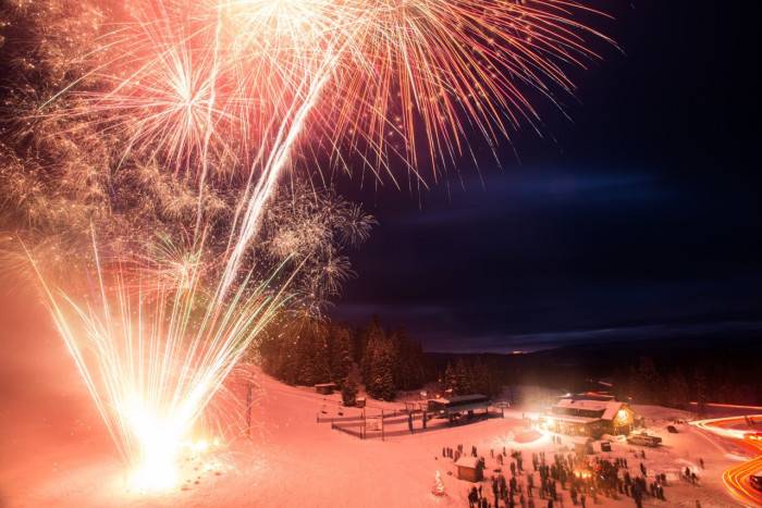 Fireworks exploding over the base of Brundage Mountain at night.