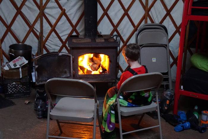 Young boy sits in front of the wood stove.