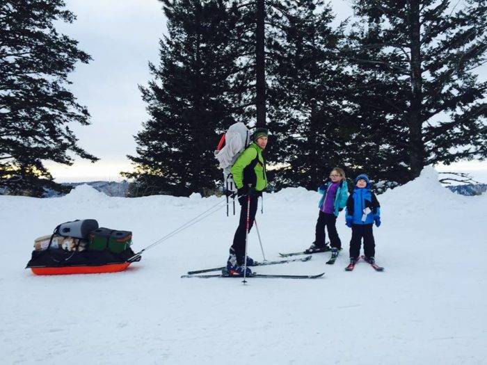 Dad with two young kids on nordic skis, dad ready to pull the sled laden with gear for an overnight stay.