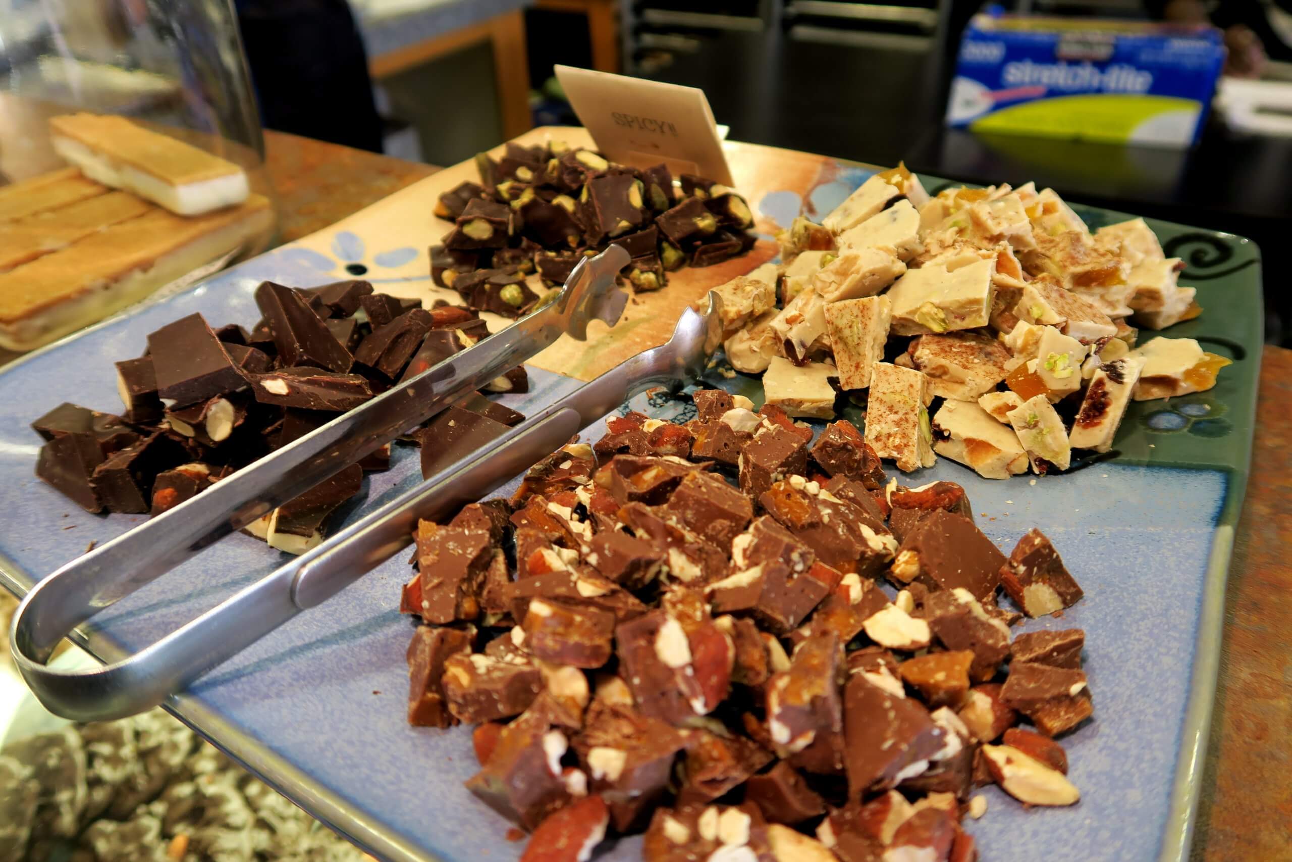 Four samples of fudge on a tray with tongs.