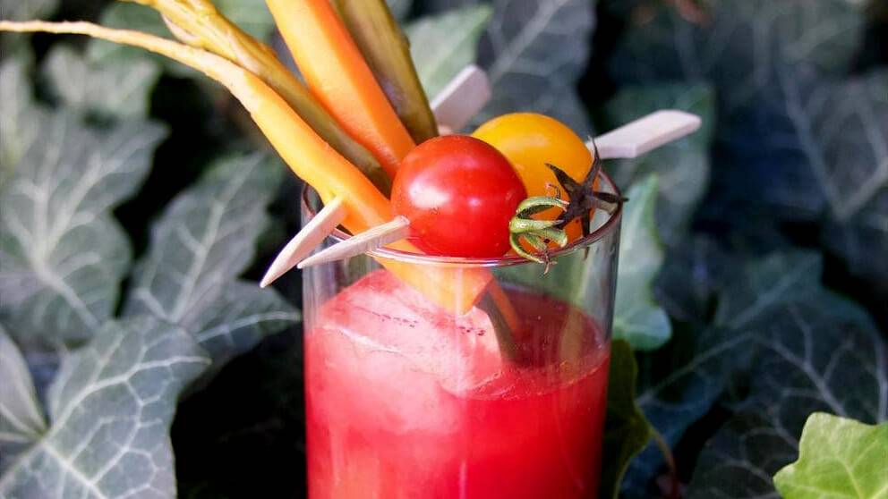 A bloody mary topped with tomatoes, carrots and pickles.