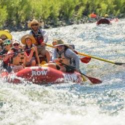 People holding paddles on a red raft navigate through white water in the Lower Salmon Canyon.