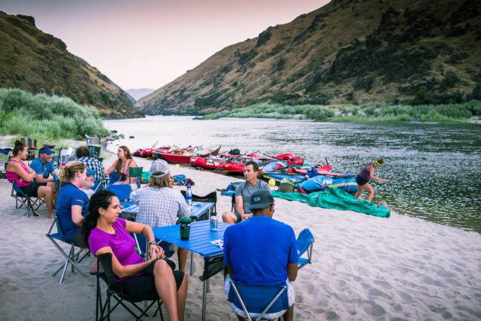 adults sitting along river