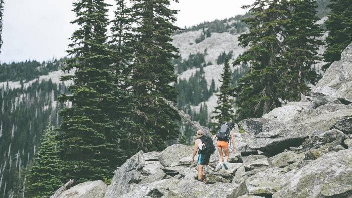 two trail runners climbing over large boulders