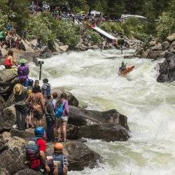 crowds sit along river at kayaking event