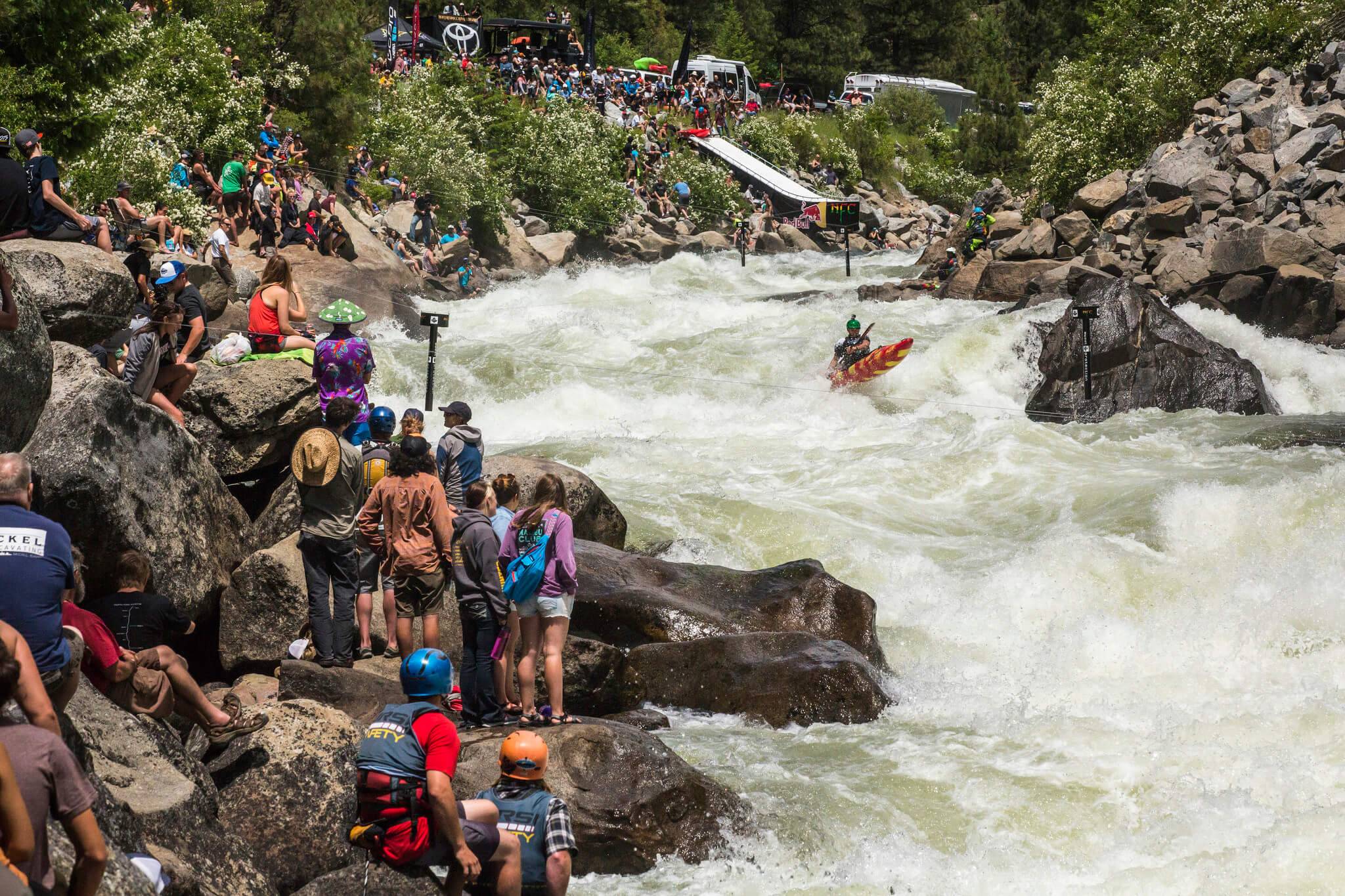 crowds sit along river at kayaking event