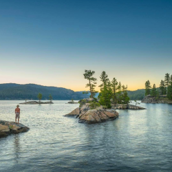 A person stands on a rock at Payette Lake.