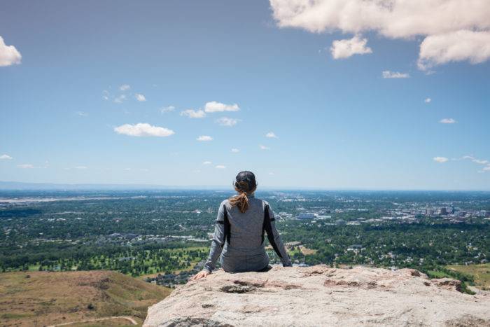 WOMAN SITTING ON ROCK LOOKING OVER VALLEY