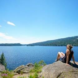 woman sitting on a rock near a lake