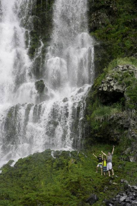 people standing next to a waterfall