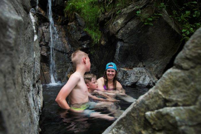 family sitting in natural hot spring