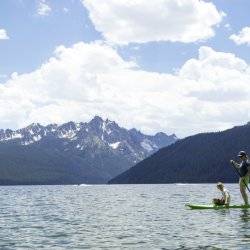 mom and son on paddleboard in mountain lake