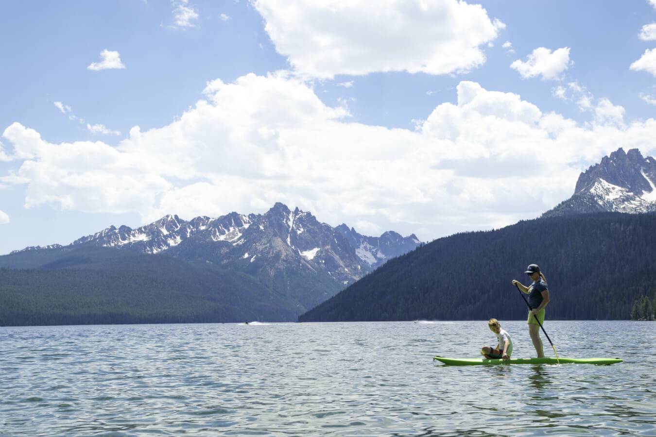 mom and son on paddleboard in mountain lake