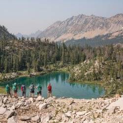 people standing on mountain looking at a lake