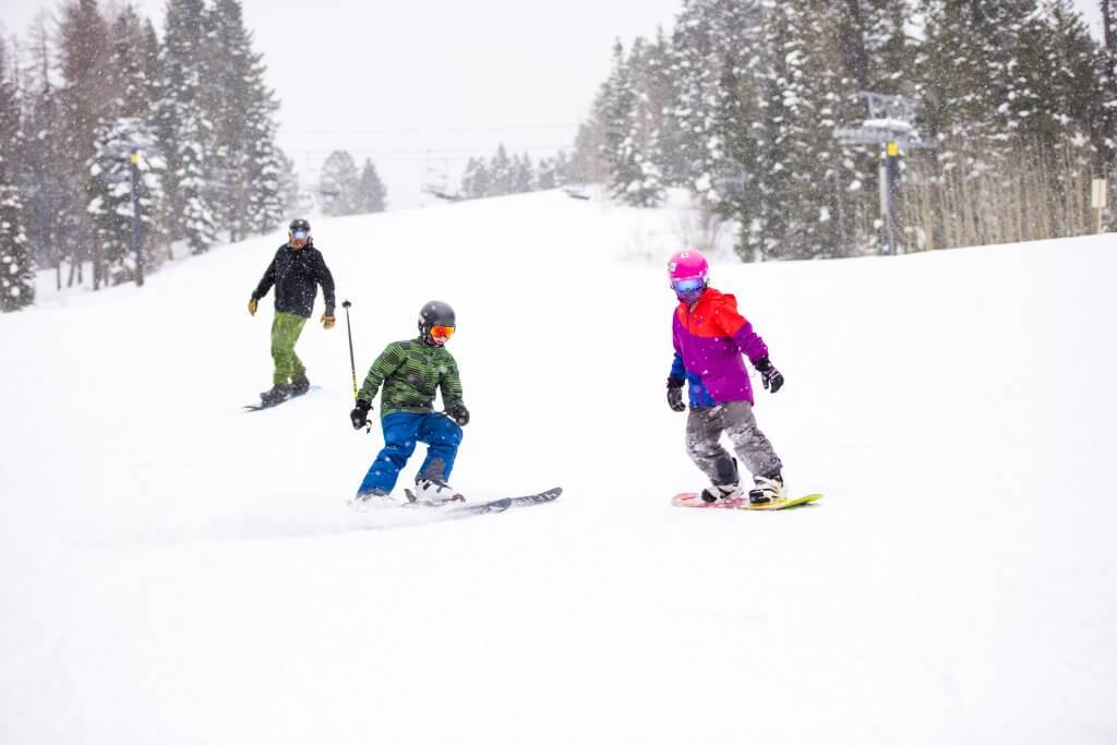 Three people ski and snowboard down a slope at Brundage Mountain Resort.