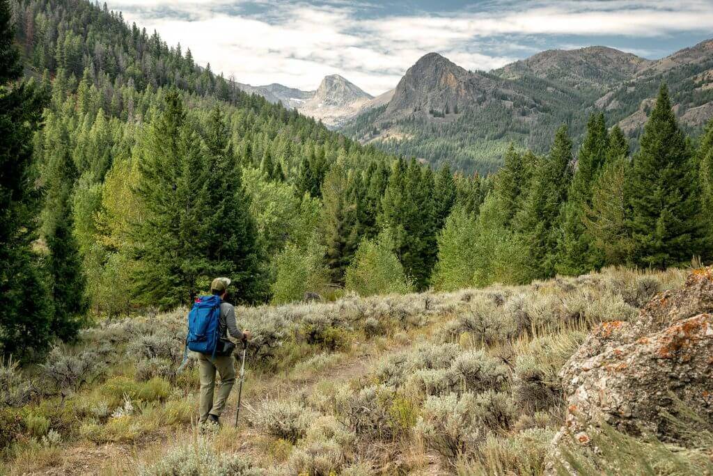 man walking on mountain trail.