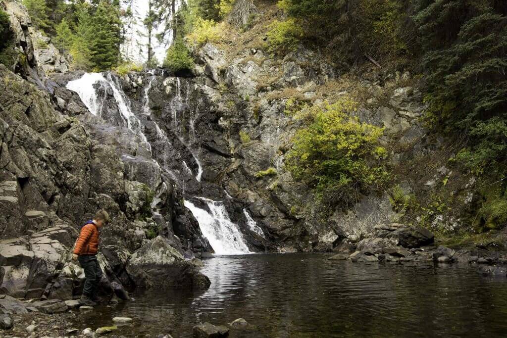 Niño jugando junto a una cascada en Goose Creek Falls.