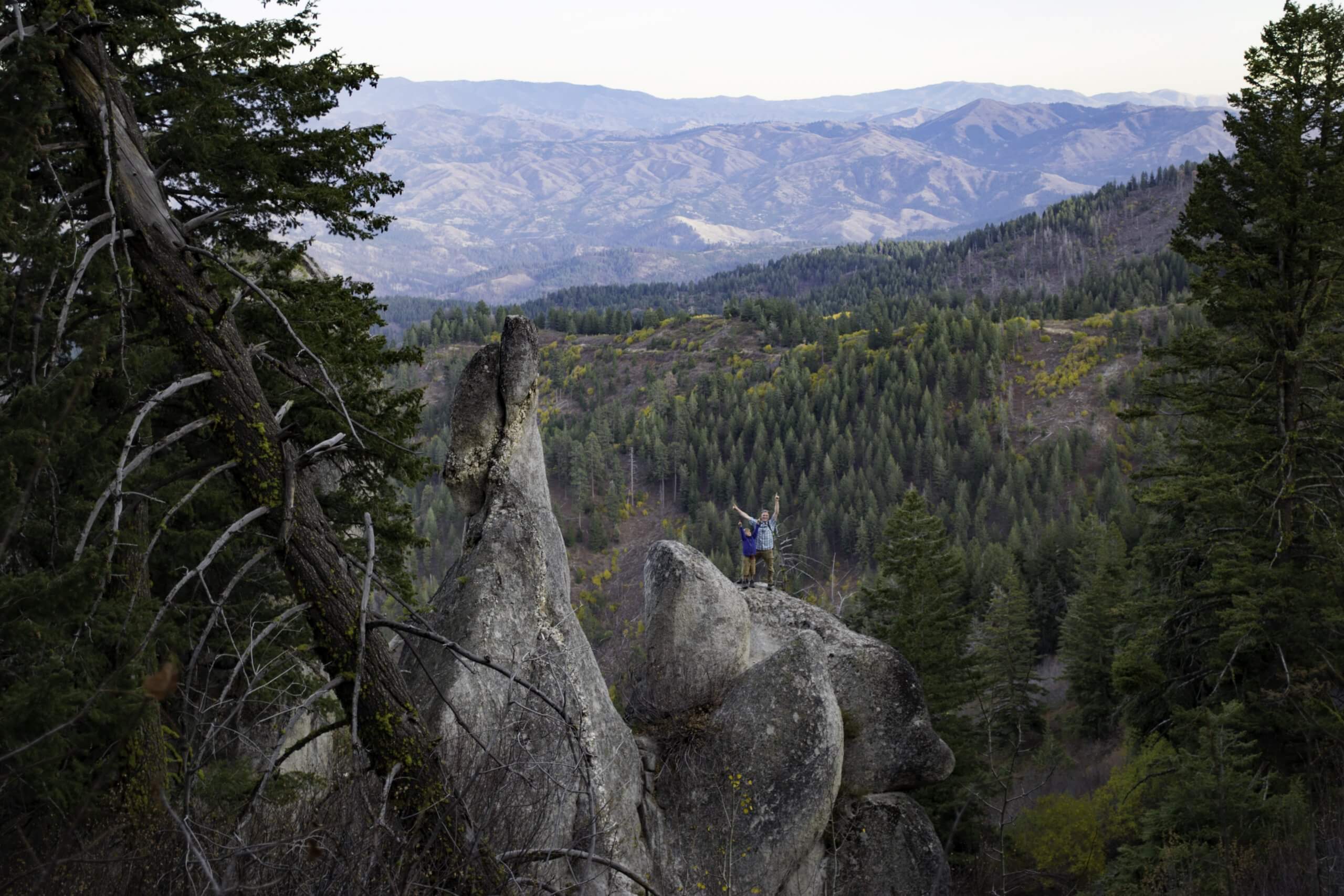 Two people standing on a rock at Mores Mountain Trail.