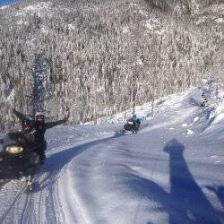 snowmobile riders enjoy a sunny trail ride in a Sandpoint valley.