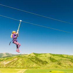 A girl ziplining at Lava Zipline Adventures with green mountains in the distance.