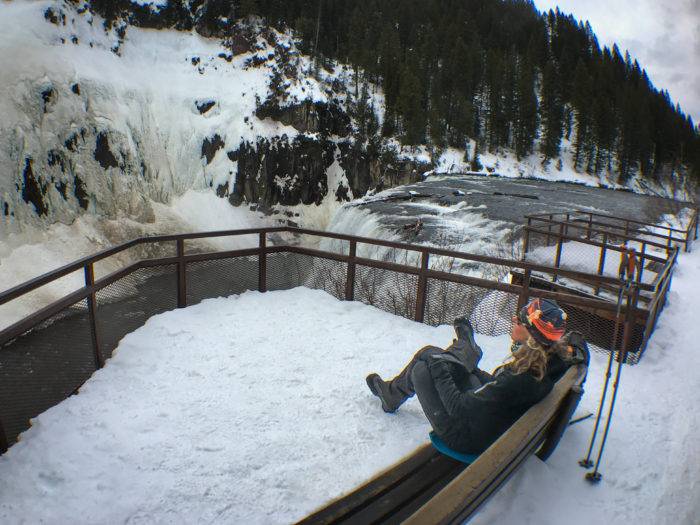 person sitting by snowy waterfall