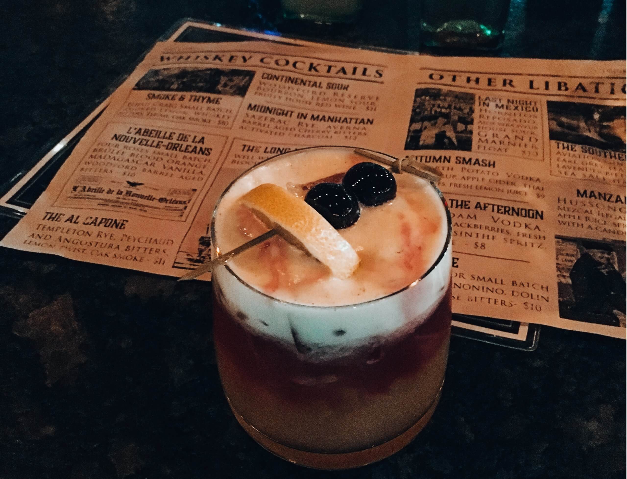 A garnished cocktail with a menu at Gas Lantern Drinking Company.