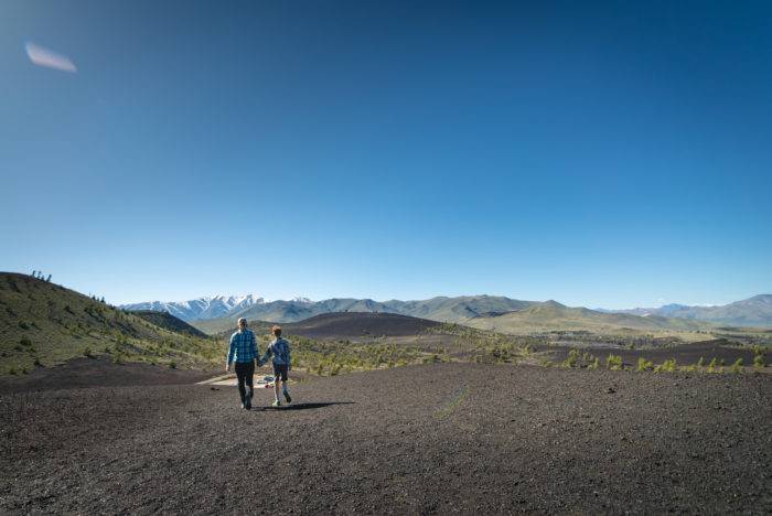 Two people hiking across the sprawling volcanic landscape at Craters of the Moon National Monument & Preserve.