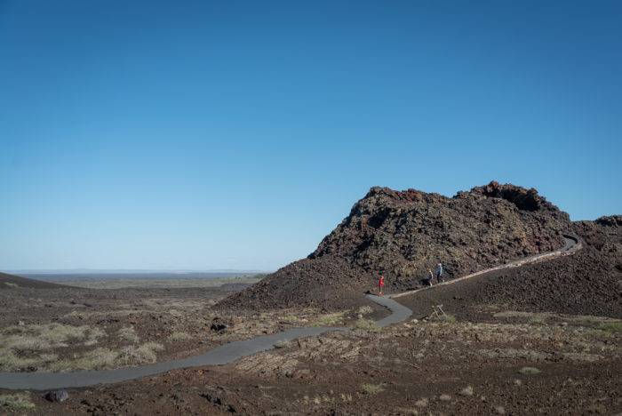 A family hiking across the sprawling volcanic landscape at Craters of the Moon National Monument & Preserve.