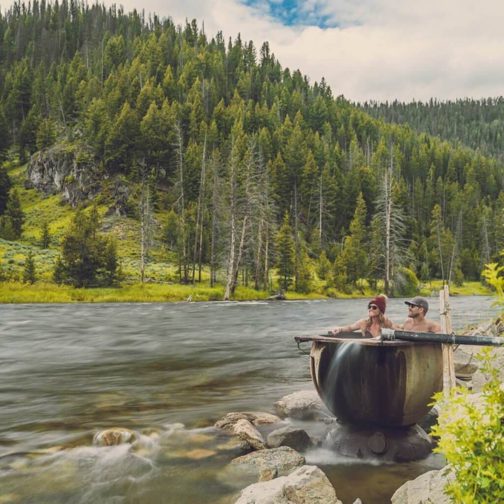 people sitting in a riverside hot tub